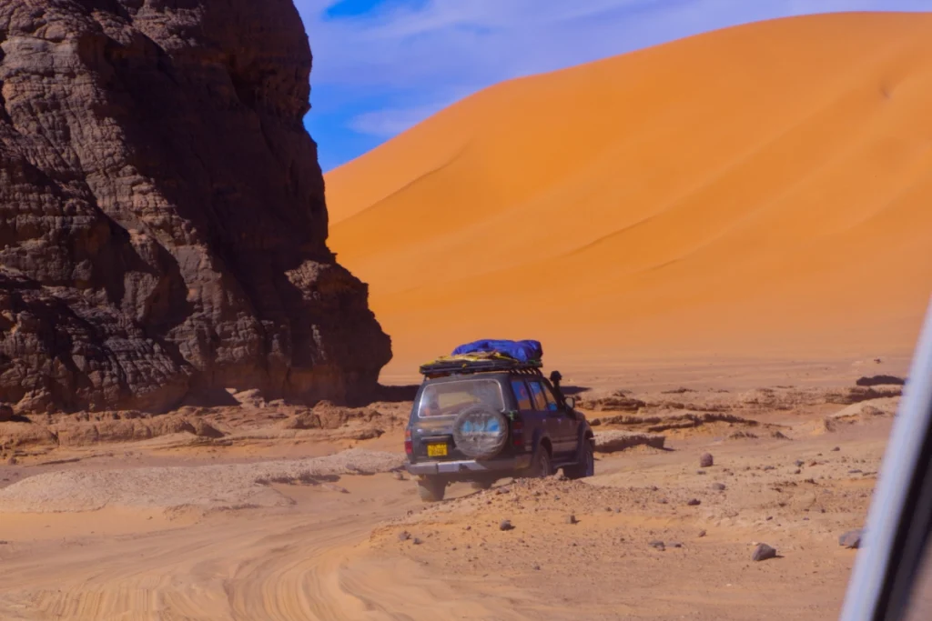 4x4 traversant le désert entre rochers et dunes du Tassili n'Ajjer